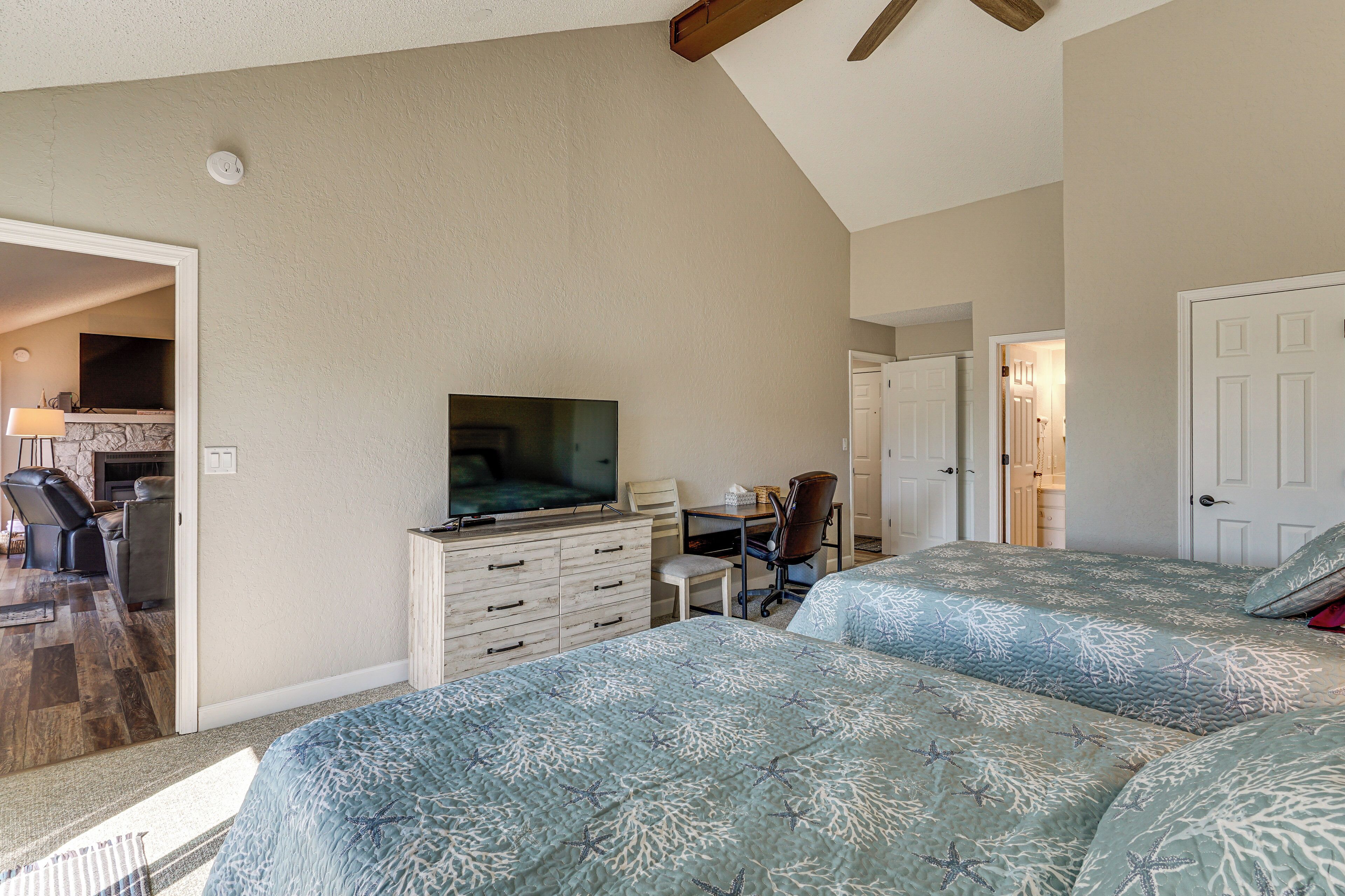 A bedroom with two beds, a desk, a chair, and a television.
