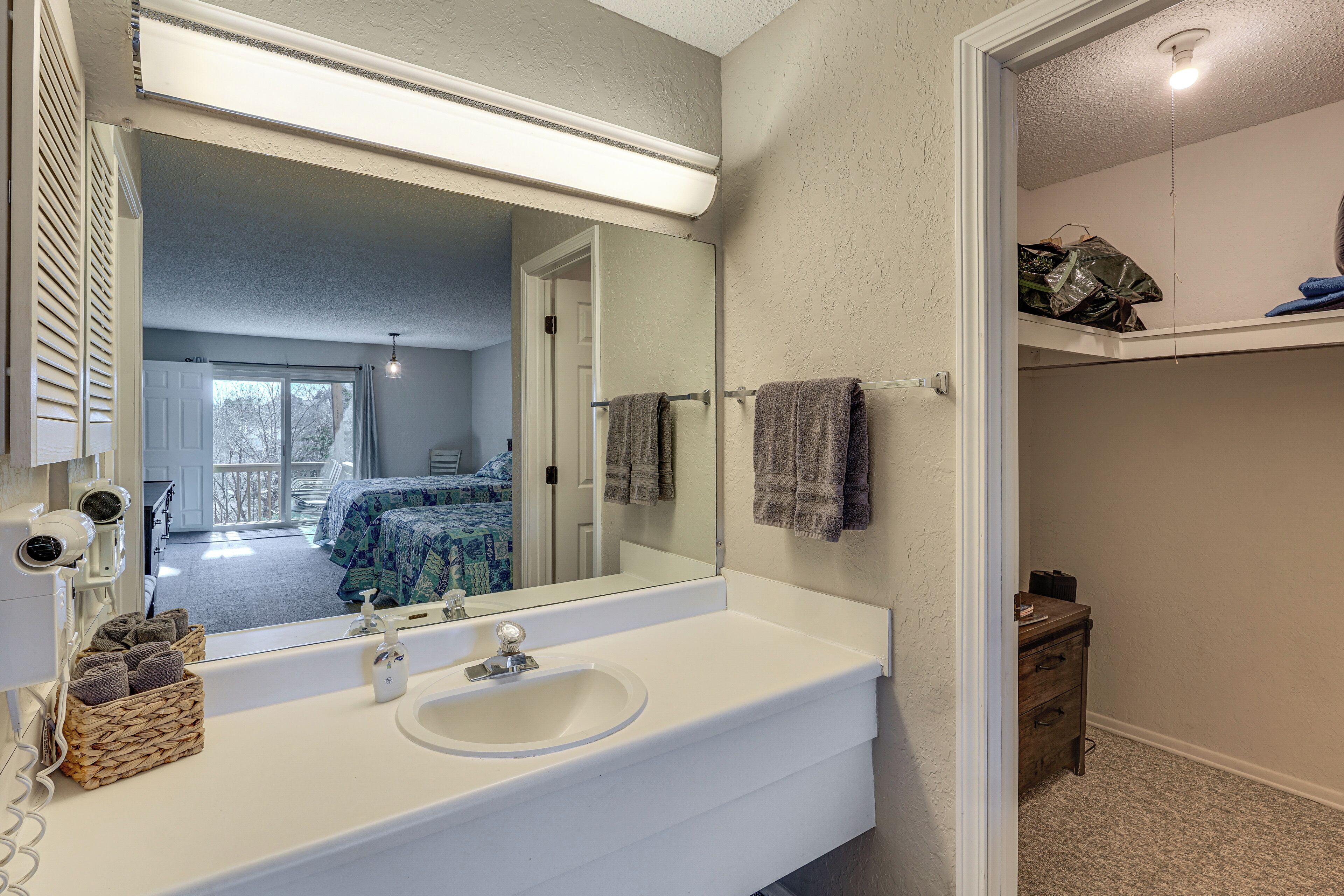 Une salle de bain avec un grand miroir, un lavabo blanc et un porte-serviettes.