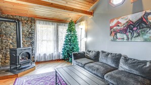 En hyggelig stue med en stenspir, en sofa, et sofabord og et juletræ.