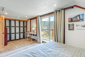 Une chambre à coucher avec un lit, un bureau et une vue sur l’extérieur.