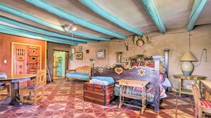 Una habitación con piso estampado, muebles de madera, una cama con cabecera decorativa y una mesa con sillas.