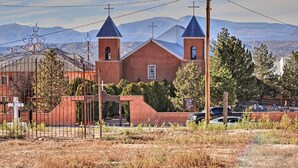 Una iglesia con dos torres y un campanario, rodeada por una valla y un área de estacionamiento.