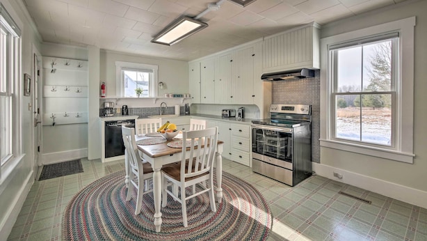 A modern kitchen with white cabinets, stainless steel appliances, and a dining area with a round rug. - Near Lakes, Bay & Trails! Historic Waldoboro Gem (Waldoboro)