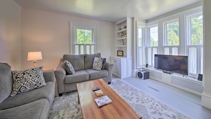 A living room with a grey sofa, a wooden coffee table, and a TV on a stand. - Near Lakes, Bay & Trails! Historic Waldoboro Gem (Waldoboro)
