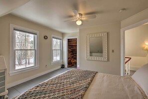 A bedroom with a large bed, a ceiling fan, a window, and a mirror. - Near Lakes, Bay & Trails! Historic Waldoboro Gem (Waldoboro)