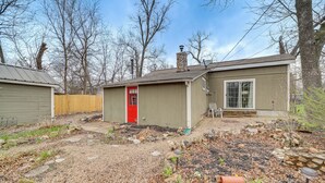A single-story house with a red door, a chimney, and a small shed. - Historic Cabin w/ Yard: 1 Mi to Lake Spavinaw! (Spavinaw)
