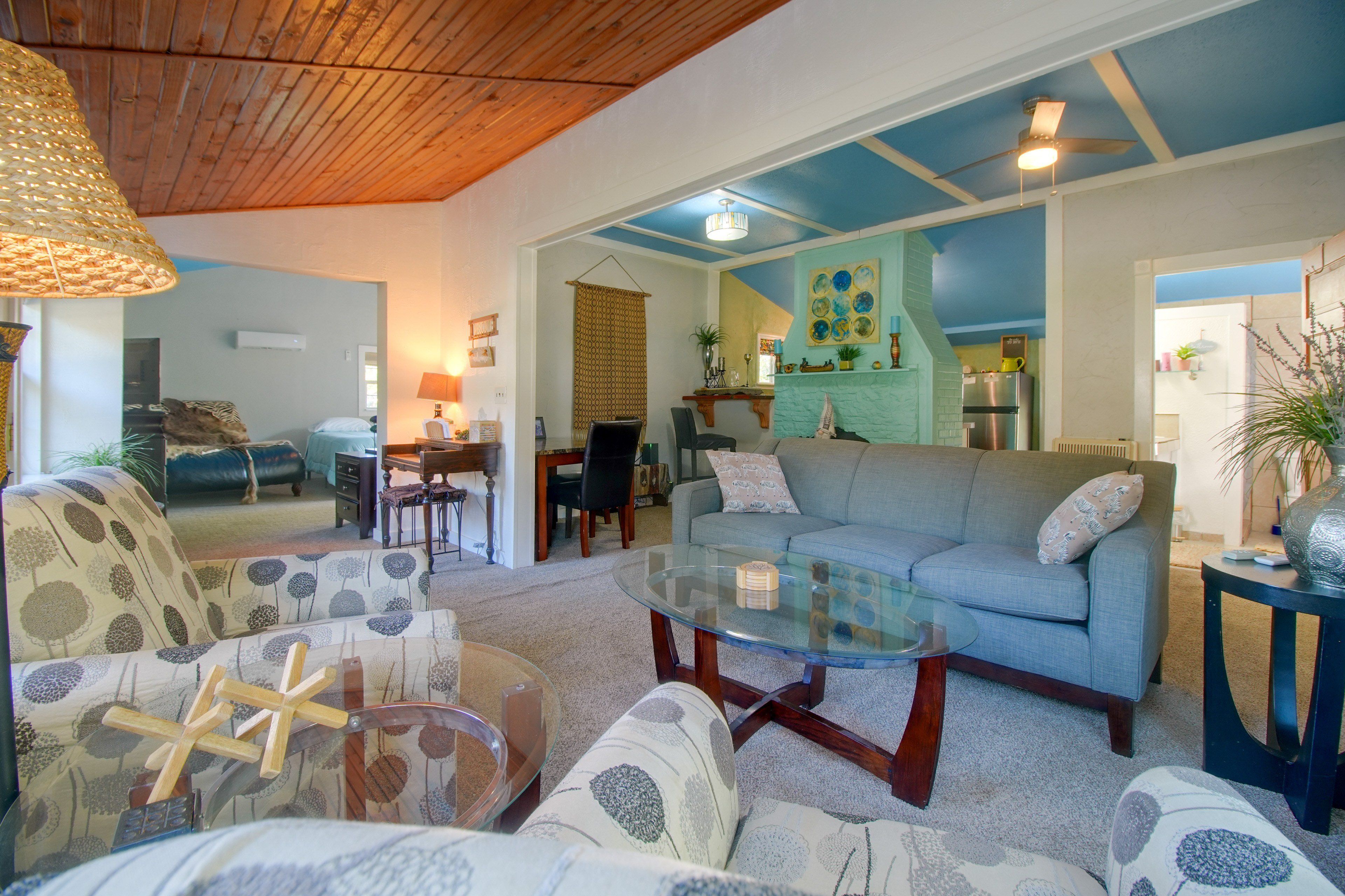 A living room with a sofa, armchairs, a glass coffee table, and a dining area with a table and chairs.