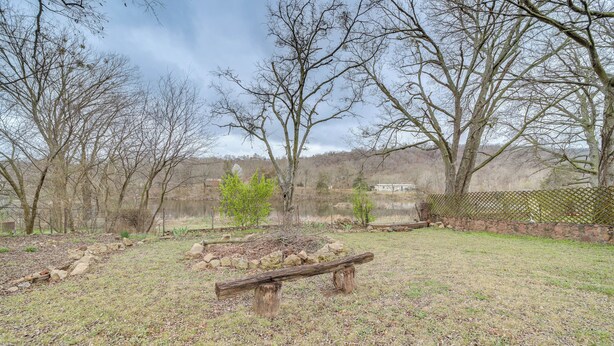A park with a wooden bench, trees, and a stone wall. - Historic Cabin w/ Yard: 1 Mi to Lake Spavinaw! (Spavinaw)