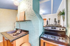 A kitchen with a brick backsplash, a sink, a stove, and a window. - Historic Cabin w/ Yard: 1 Mi to Lake Spavinaw! (Spavinaw)