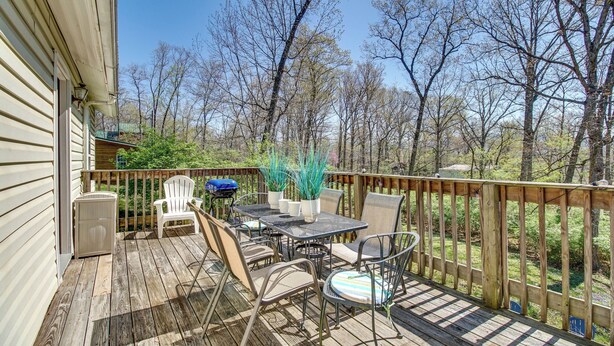Une terrasse en bois aménagée avec du mobilier d’extérieur, notamment une table et des chaises, ainsi qu’un barbecue.