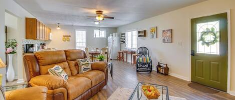 A spacious living room with a leather sofa, a glass coffee table, and a dining area with a white table and chairs.