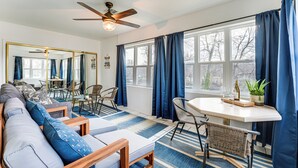 A modern living room with a sofa, a dining table, and a ceiling fan. - Sunroom, Fireplace: Lakefront Branson Condo (Branson)