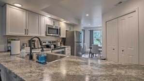 A modern kitchen with white cabinets, stainless steel appliances, and a granite countertop. - Sunroom, Fireplace: Lakefront Branson Condo (Branson)