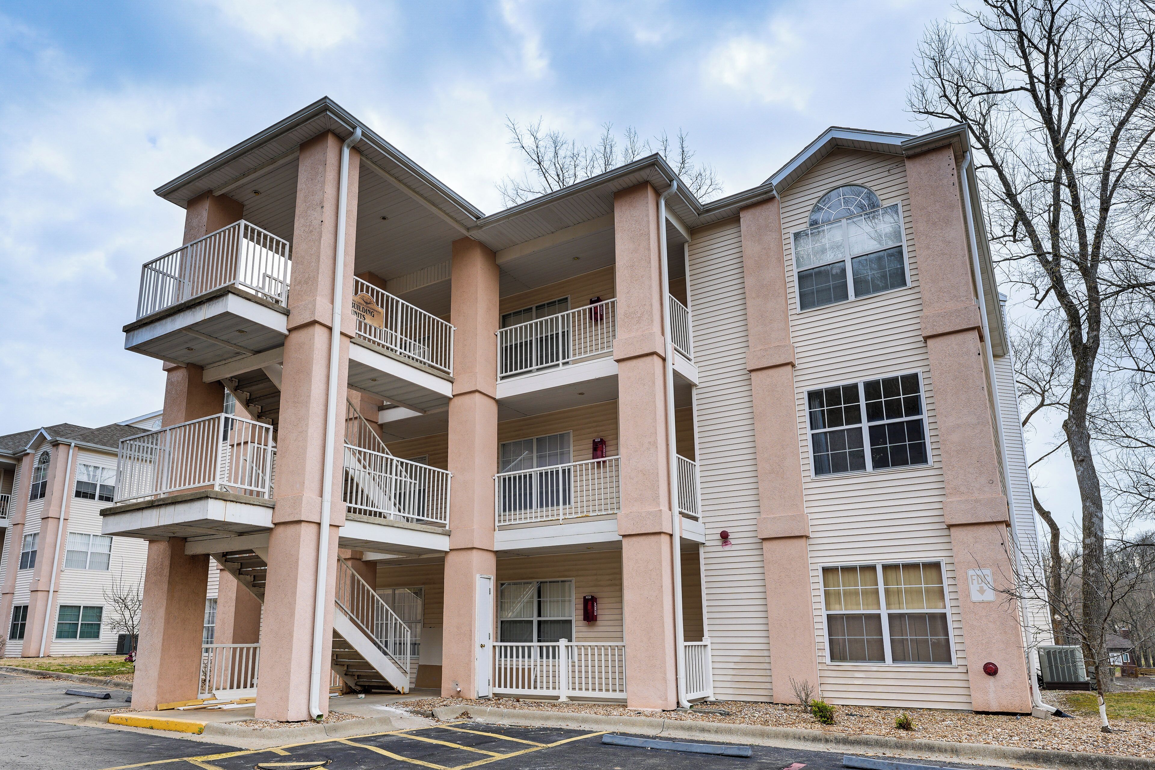A multi-story building with balconies, staircases, and a parking lot.