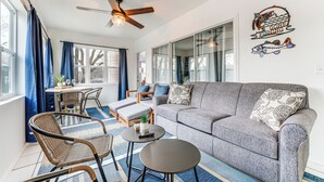 A modern living room with a grey sofa, wicker chairs, a small round table, and a ceiling fan. - Sunroom, Fireplace: Lakefront Branson Condo (Branson)
