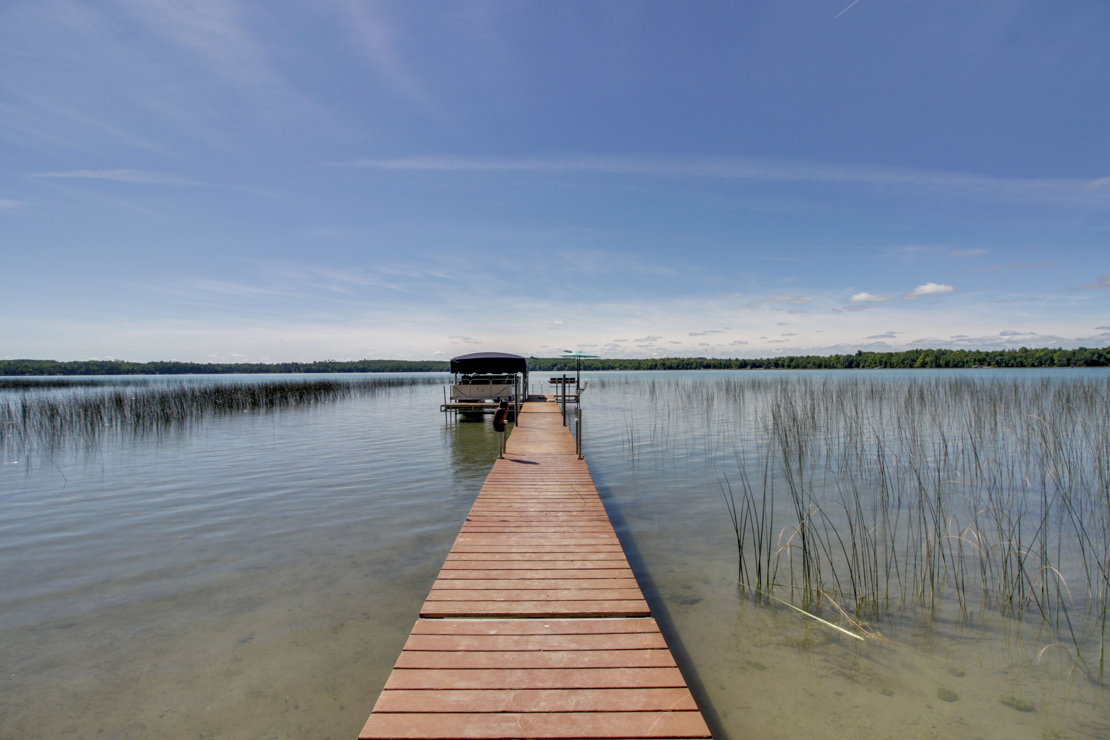 Una banchina di legno si protende su un lago calmo, con un cielo sereno.
