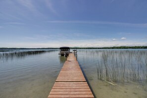 Une jetée en bois s’étendant sur un lac paisible, sous un ciel dégagé.