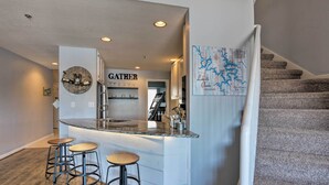 A modern kitchen with a central island, bar stools, and a 'GATHER' sign. - Clifftop Kaiser Condo for Shootout Weekend Groups (Kaiser)