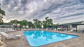 A swimming pool with lounge chairs and a covered area, surrounded by trees and a cloudy sky. - Clifftop Kaiser Condo for Shootout Weekend Groups (Kaiser)
