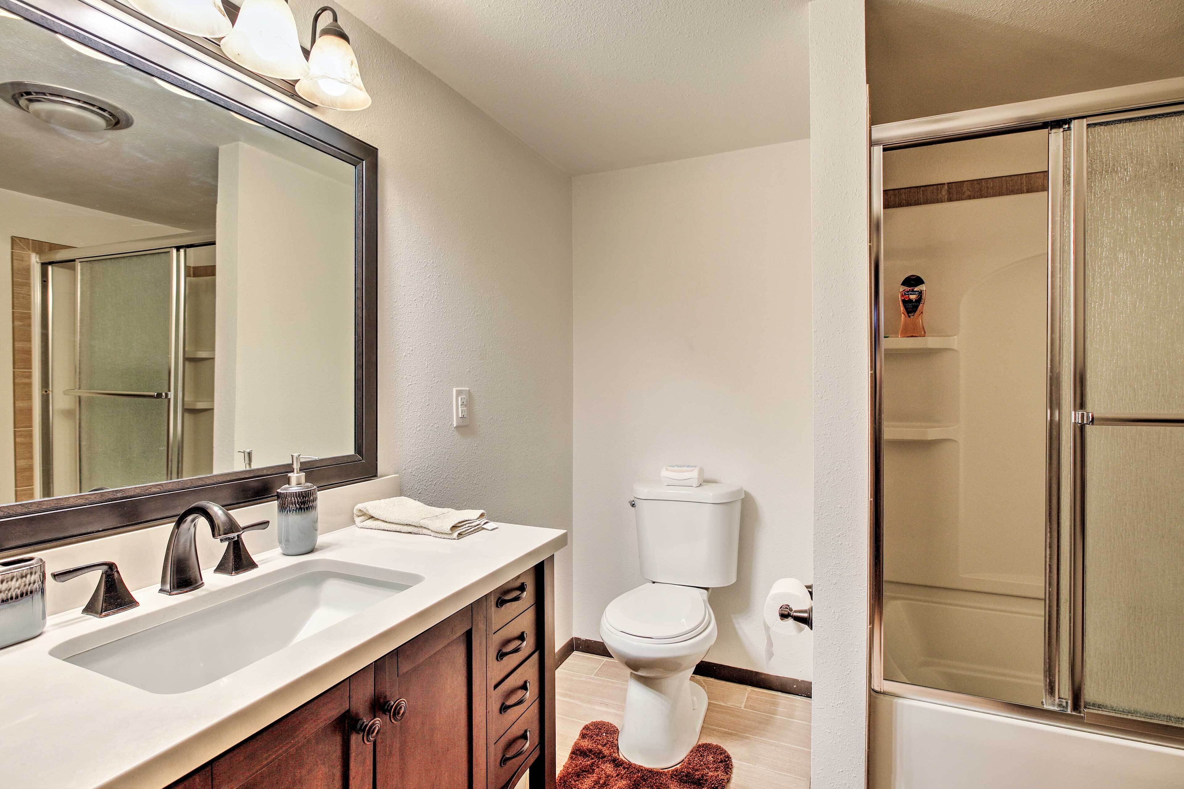 Een badkamer met een grote spiegel, een wastafel, toilet en een douche.