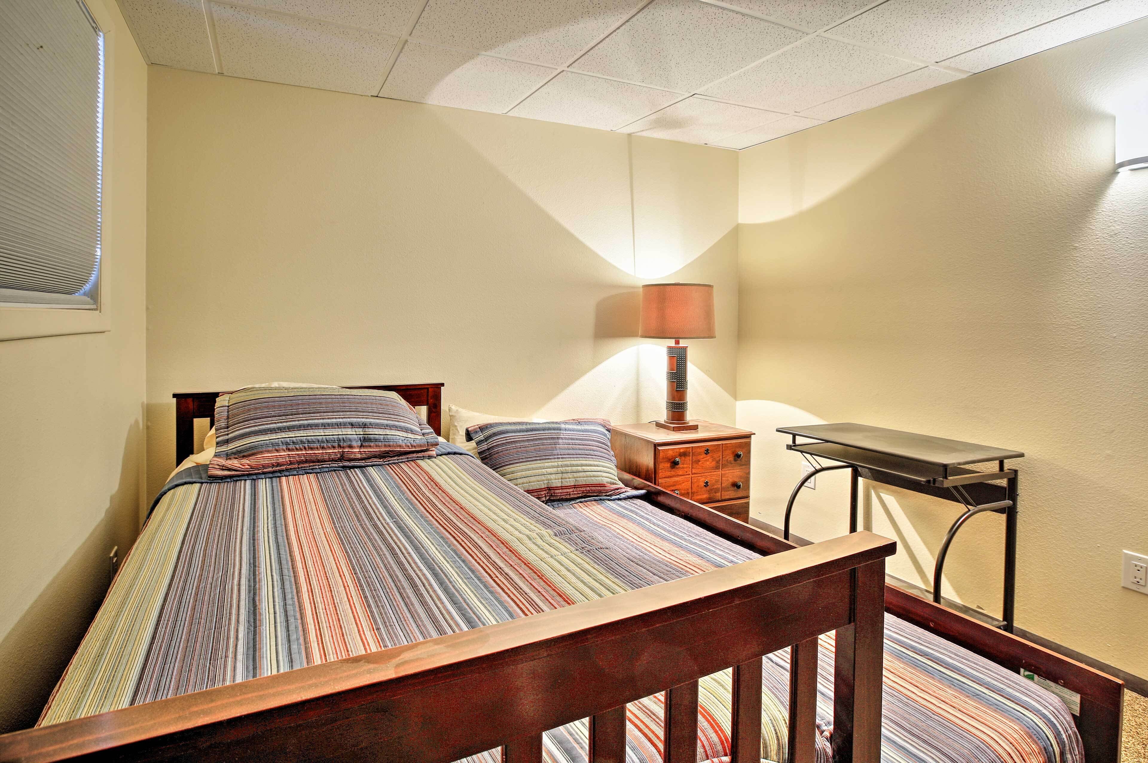 A bedroom with a bed, a nightstand, a lamp, and a desk.