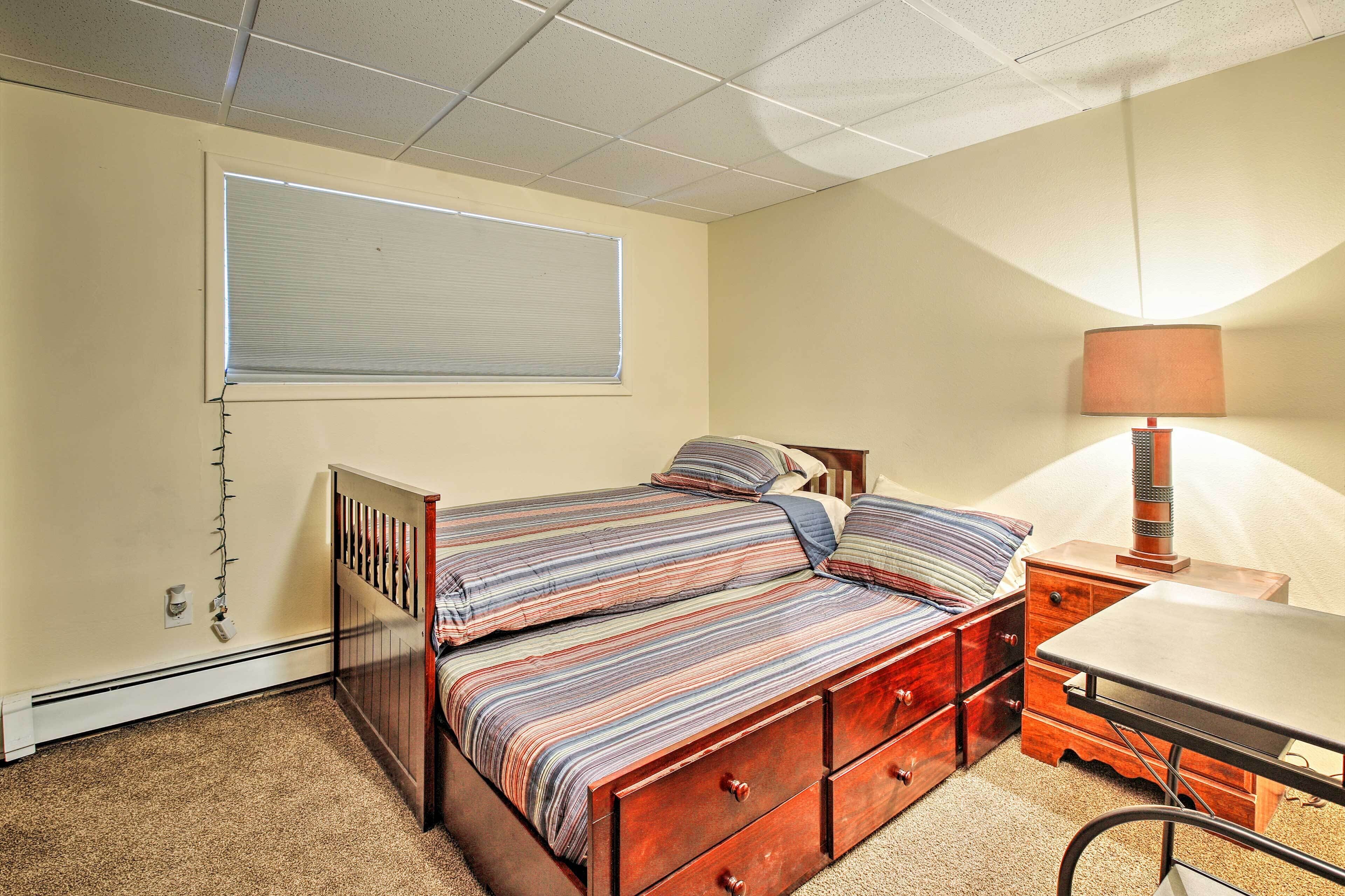 A bedroom with a bed, a nightstand, a lamp, and a window with blinds.