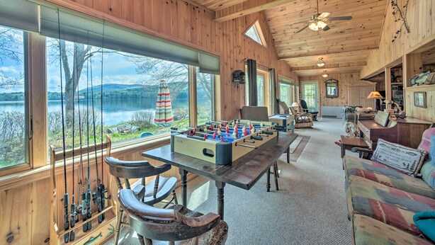 A cozy wooden cabin with a foosball table, fishing rods, and a large window overlooking a lake. - Waterfront Lake Pleasant Getaway w/ Kayaks, Grill! (Lake Pleasant)