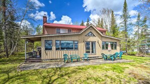 A wooden cabin with a red roof, large windows, and outdoor seating. - Waterfront Lake Pleasant Getaway w/ Kayaks, Grill! (Lake Pleasant)