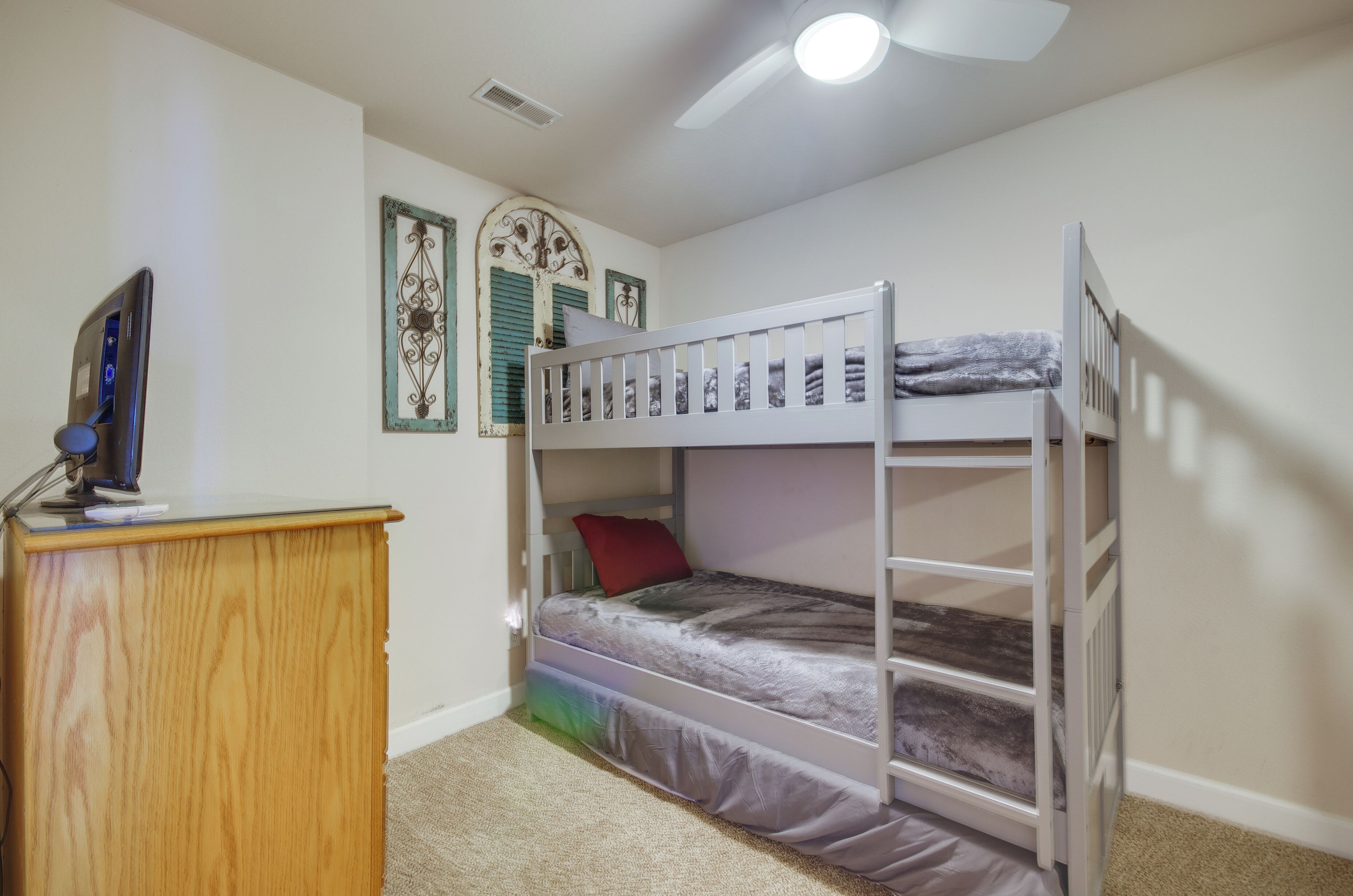A bunk bed room with a desk and a ceiling fan.