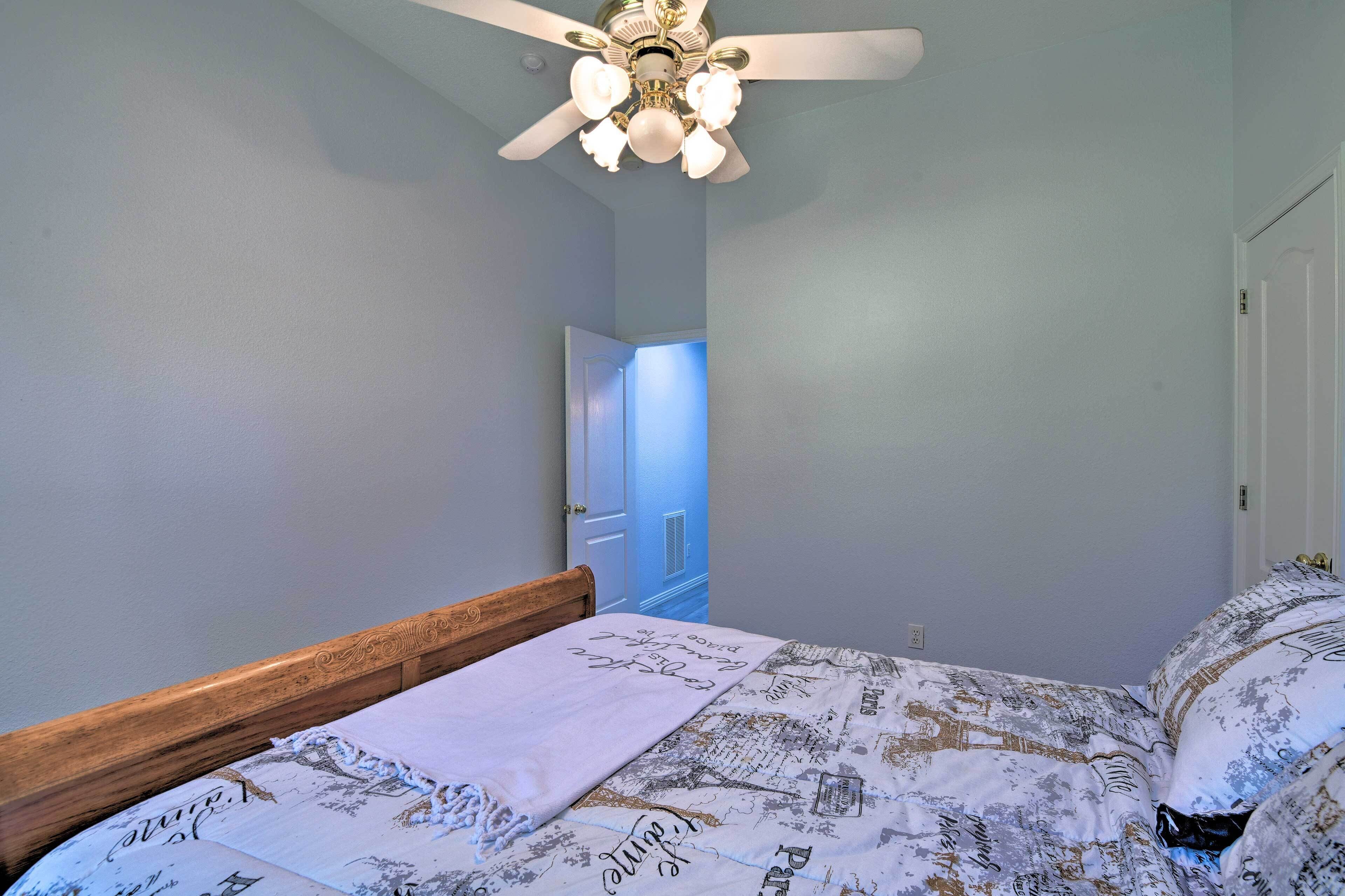 Une chambre à coucher avec un lit, un ventilateur de plafond, une porte et un mur.