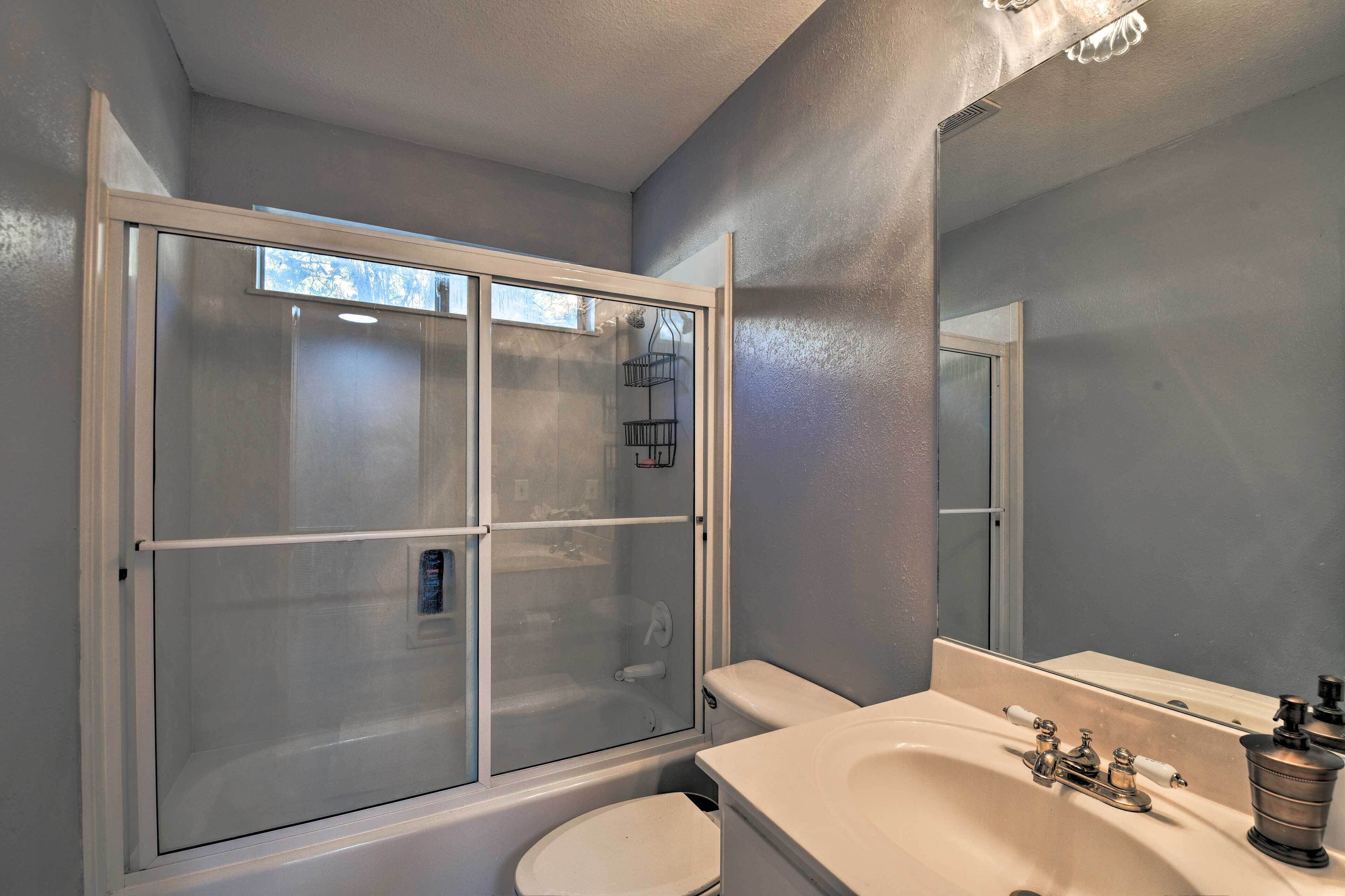 A bathroom with a glass-enclosed shower, a white toilet, and a sink with a mirror.