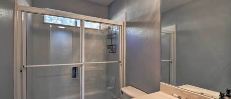A bathroom with a glass-enclosed shower, a white toilet, and a sink with a mirror.