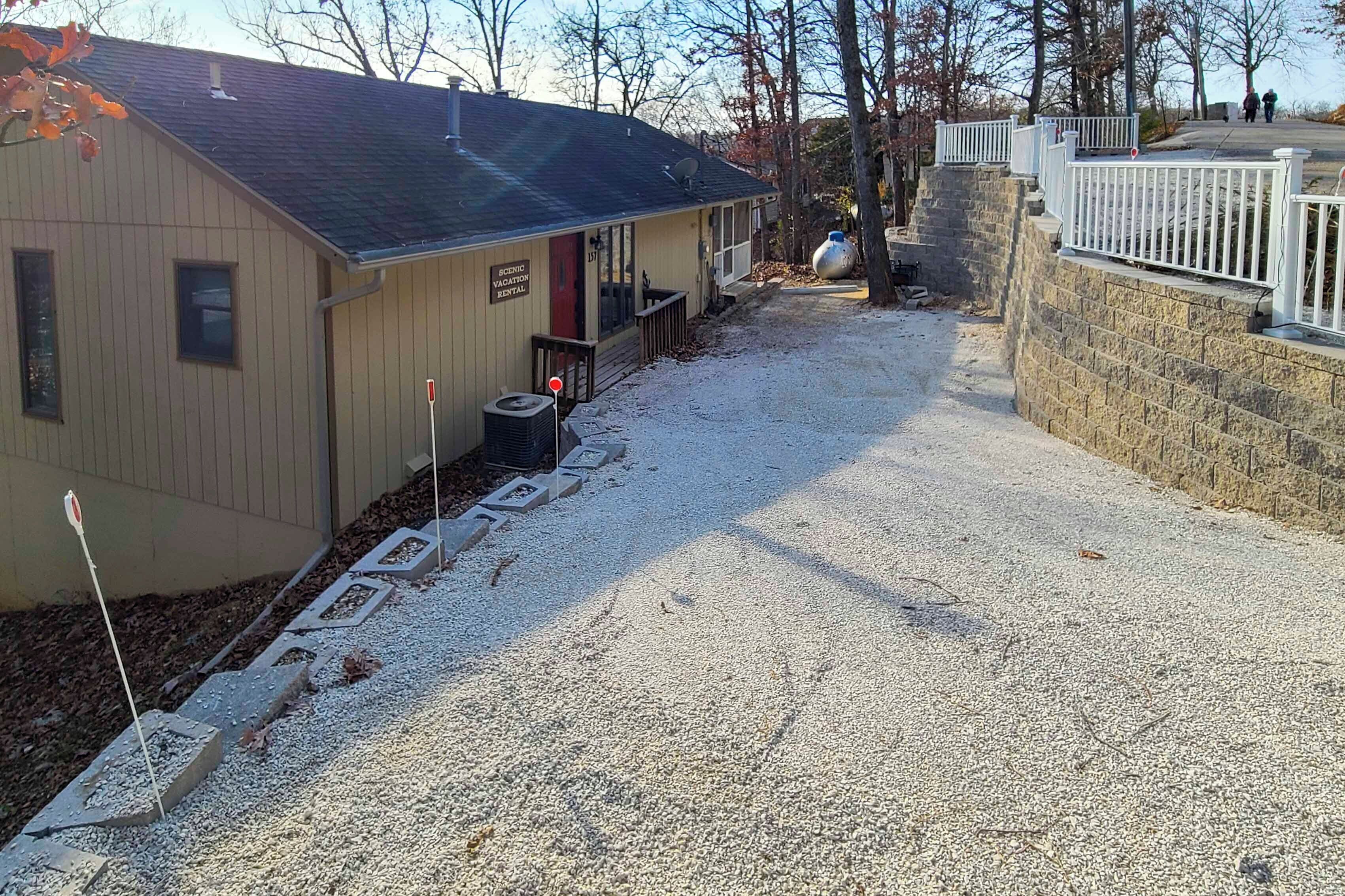 A building with a gravel driveway, a red door, and a sign indicating a vacant rental.