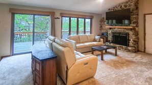 A living room with a sofa, a recliner, a coffee table, a fireplace, and a stone wall. - Boat Dock! Lakefront Group Getaway in Eldon (Eldon)