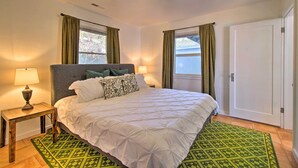 A bedroom with a bed, two bedside lamps, a green patterned rug, and two windows with curtains. - Lakefront Sanctuary w/ Mount Konocti Views (Nice)