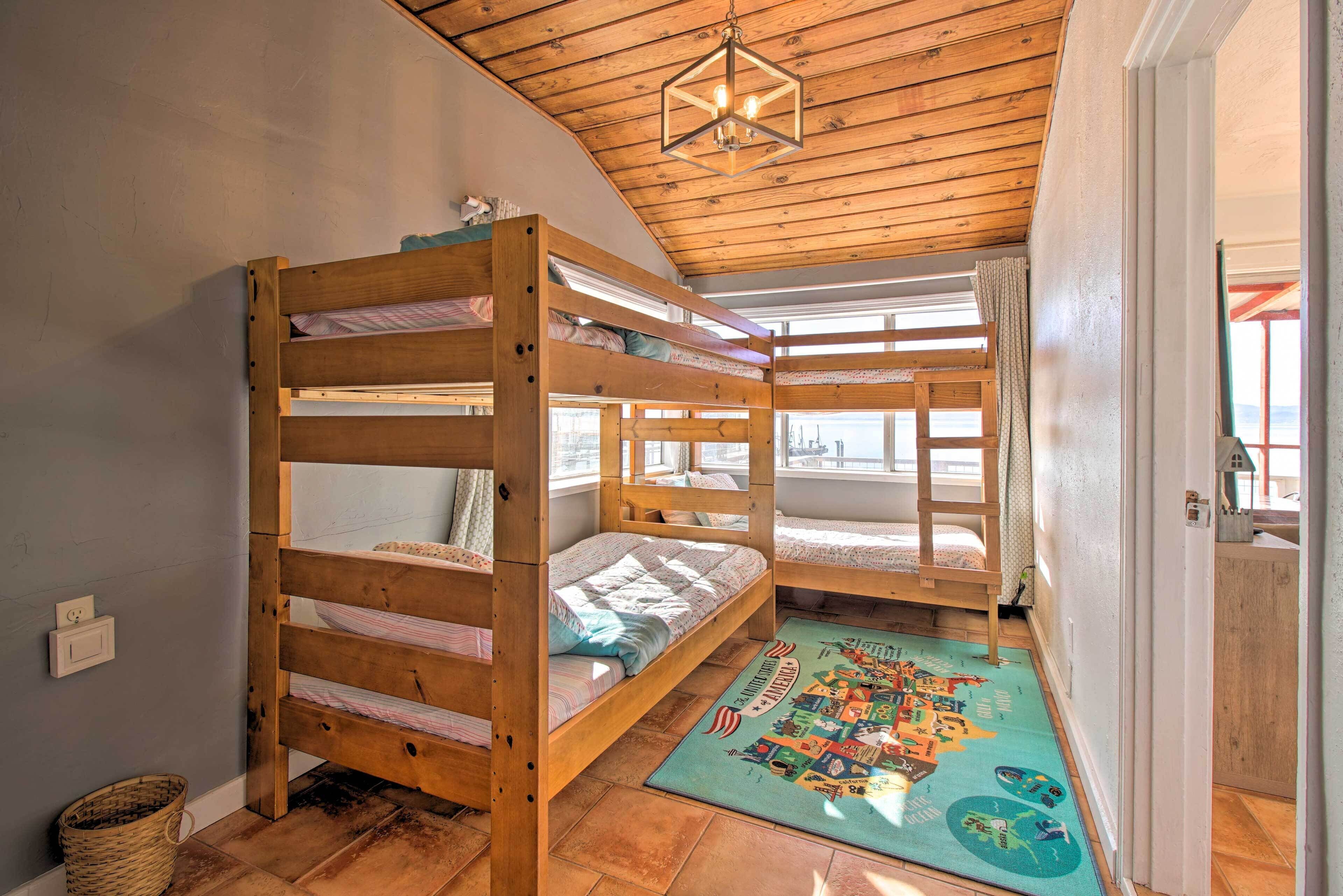 Une pièce avec trois lits superposés, un plafond en bois et un tapis aux couleurs vives.