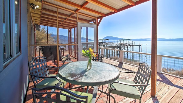 A covered outdoor seating area with a table and chairs, overlooking a body of water and distant mountains. - Lakefront Sanctuary w/ Mount Konocti Views (Nice)