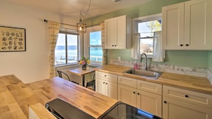 A kitchen with wooden countertops, white cabinets, a sink, and a dining area with a table and chairs. - Lakefront Sanctuary w/ Mount Konocti Views (Nice)
