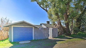 A single-story house with a blue garage door, a wooden fence, and a large tree in the background. - Lakefront Sanctuary w/ Mount Konocti Views (Nice)