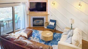 A living room with a fireplace, a television, and a balcony view.