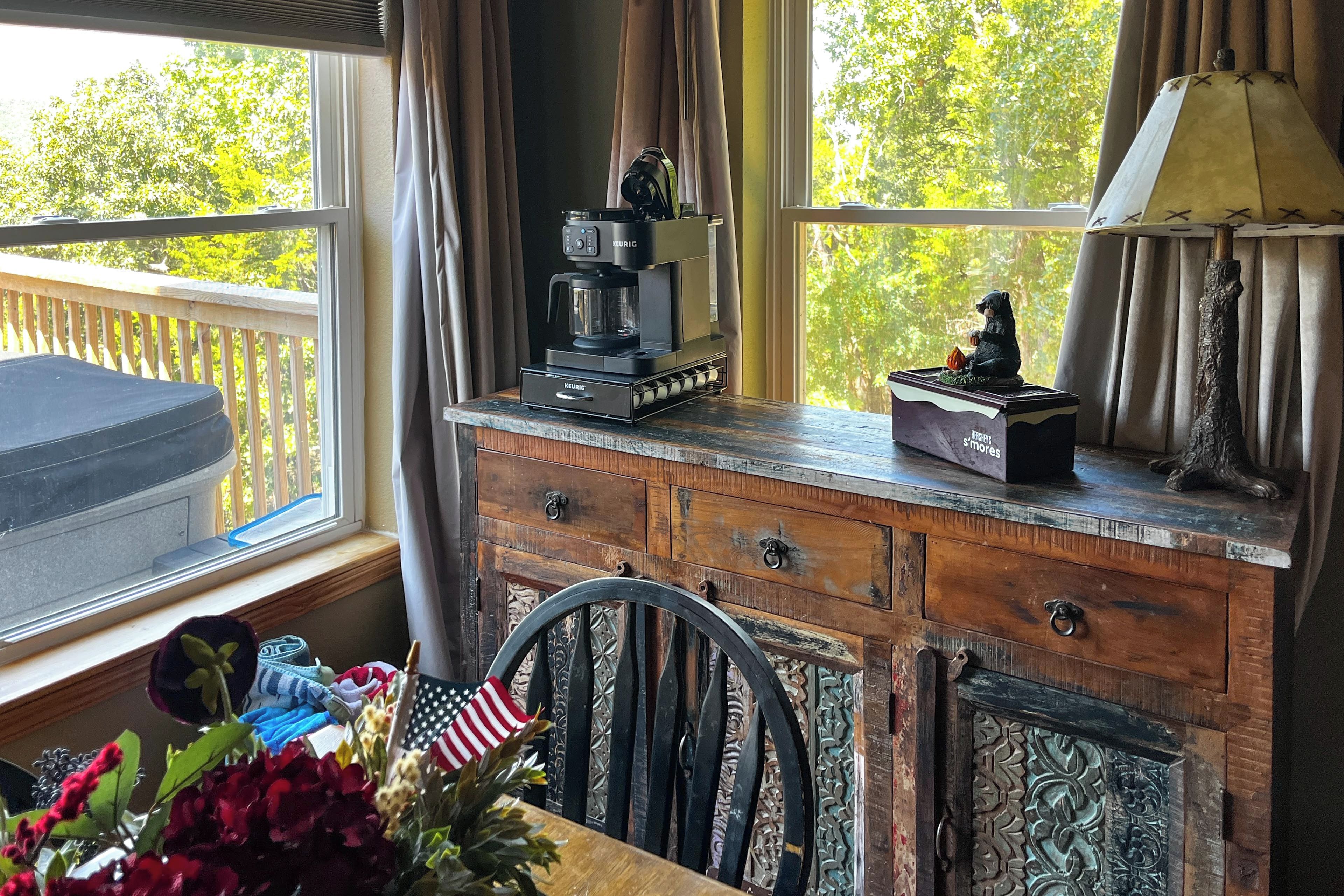 A wooden desk with a coffee maker, a lamp, and a bear figurine.
