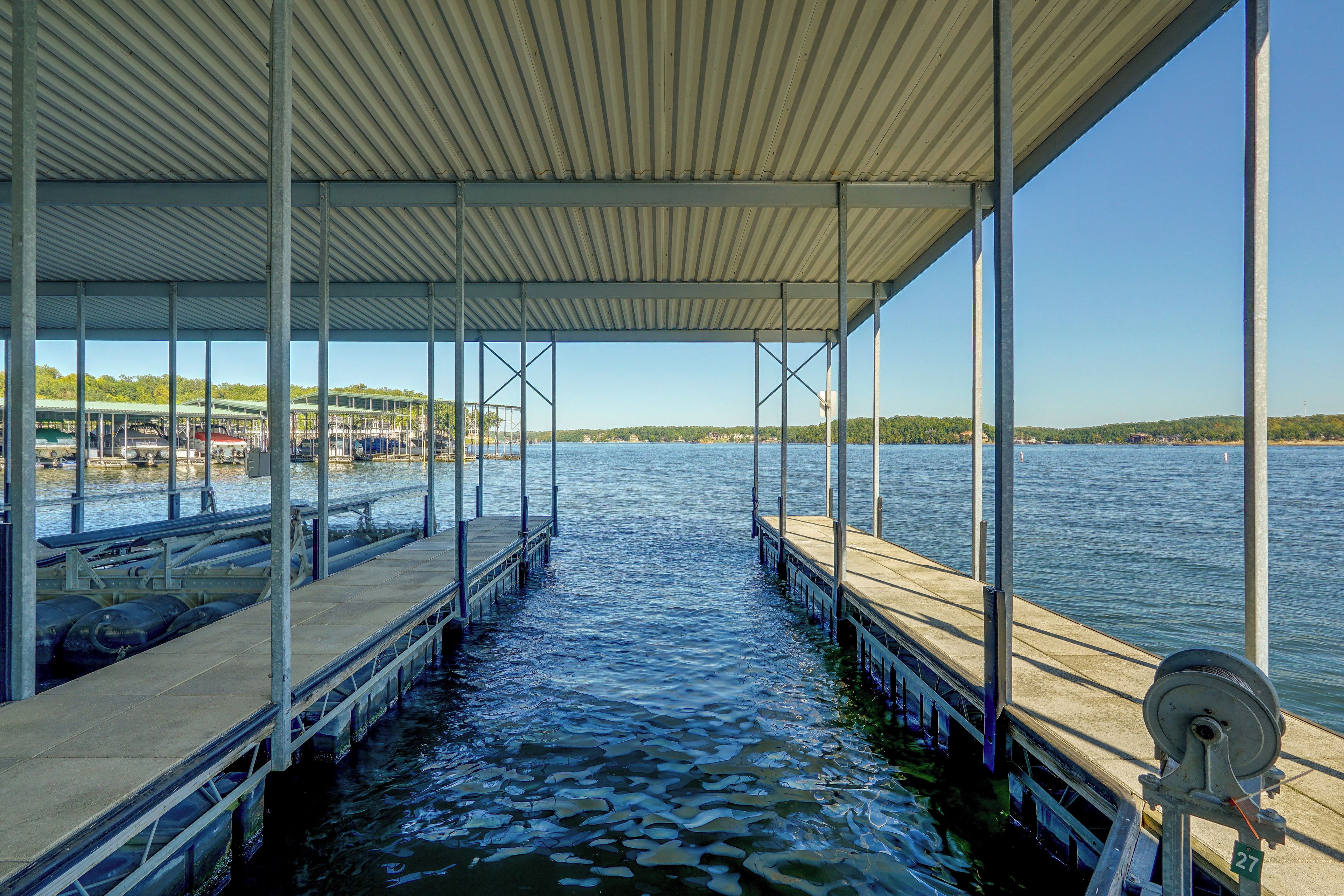 A covered dock extending into a calm body of water with a clear sky above.