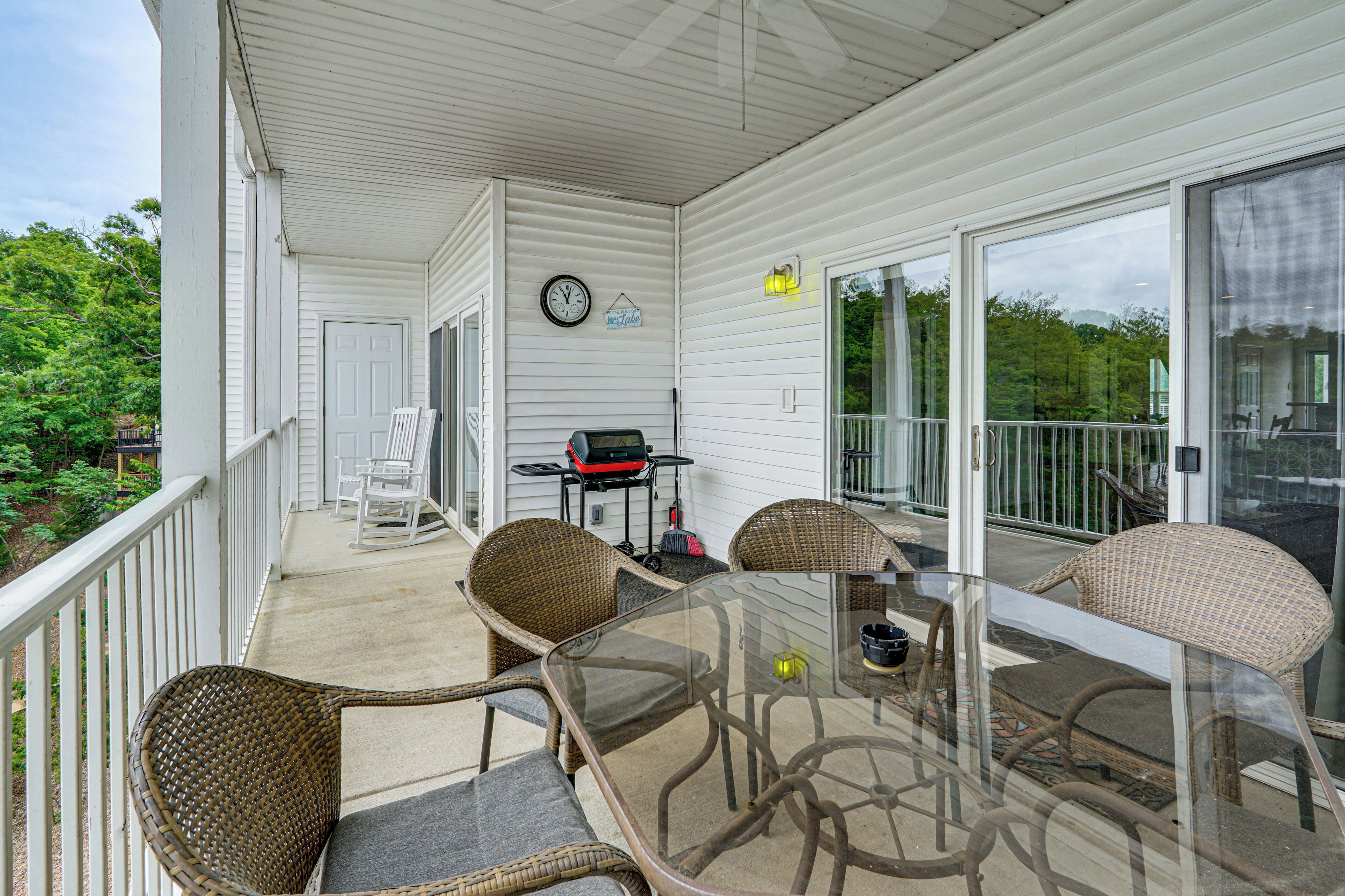 A covered patio with wicker chairs, a glass table, and a clock on the wall.