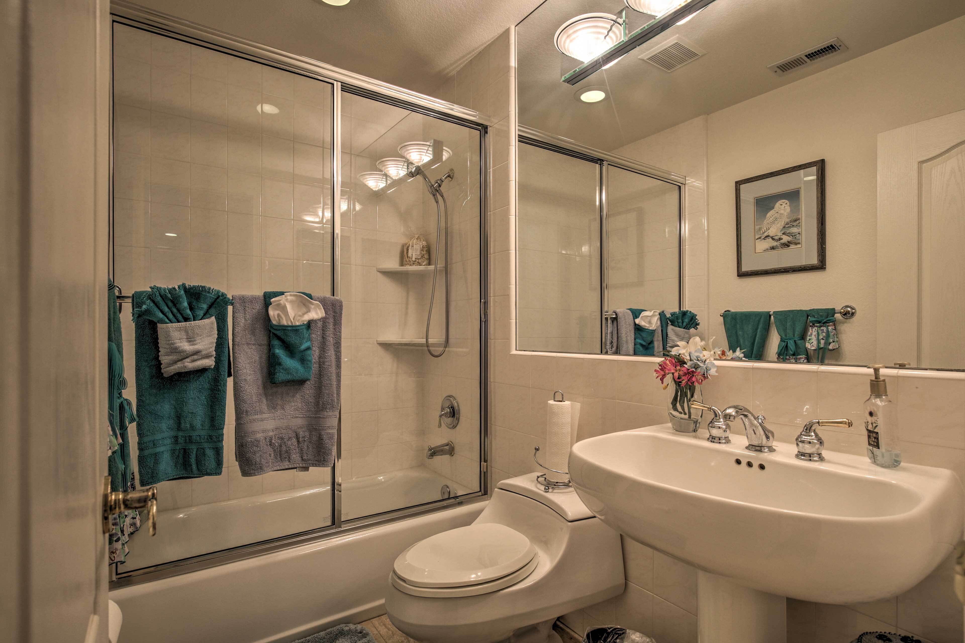 A bathroom with a glass-enclosed shower, a toilet, and a sink with a mirror above it.