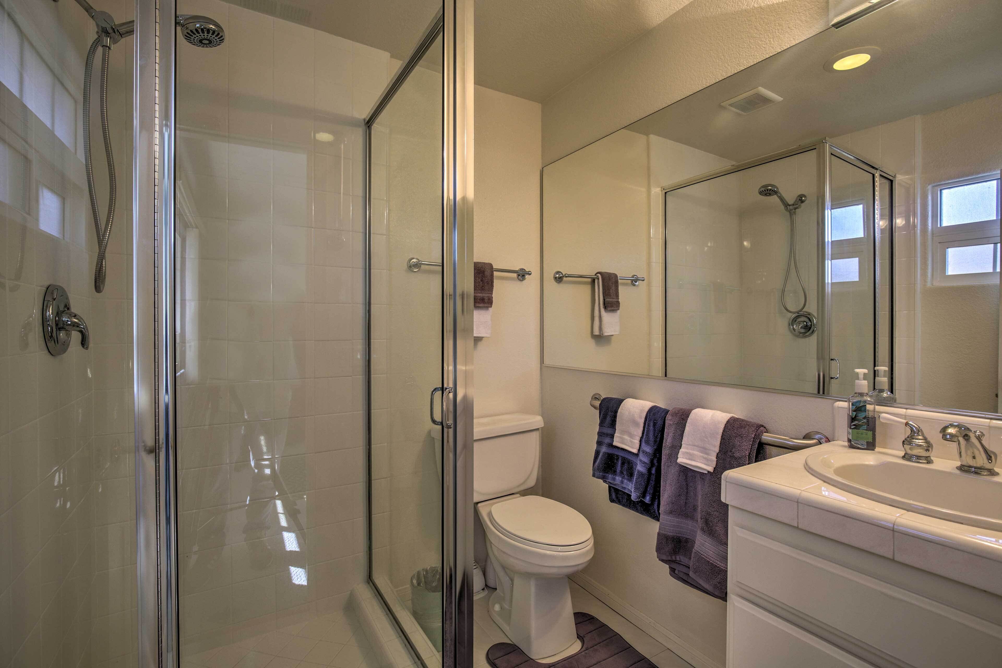 A modern bathroom with a glass-enclosed shower, a white toilet, and a large mirror above the sink.