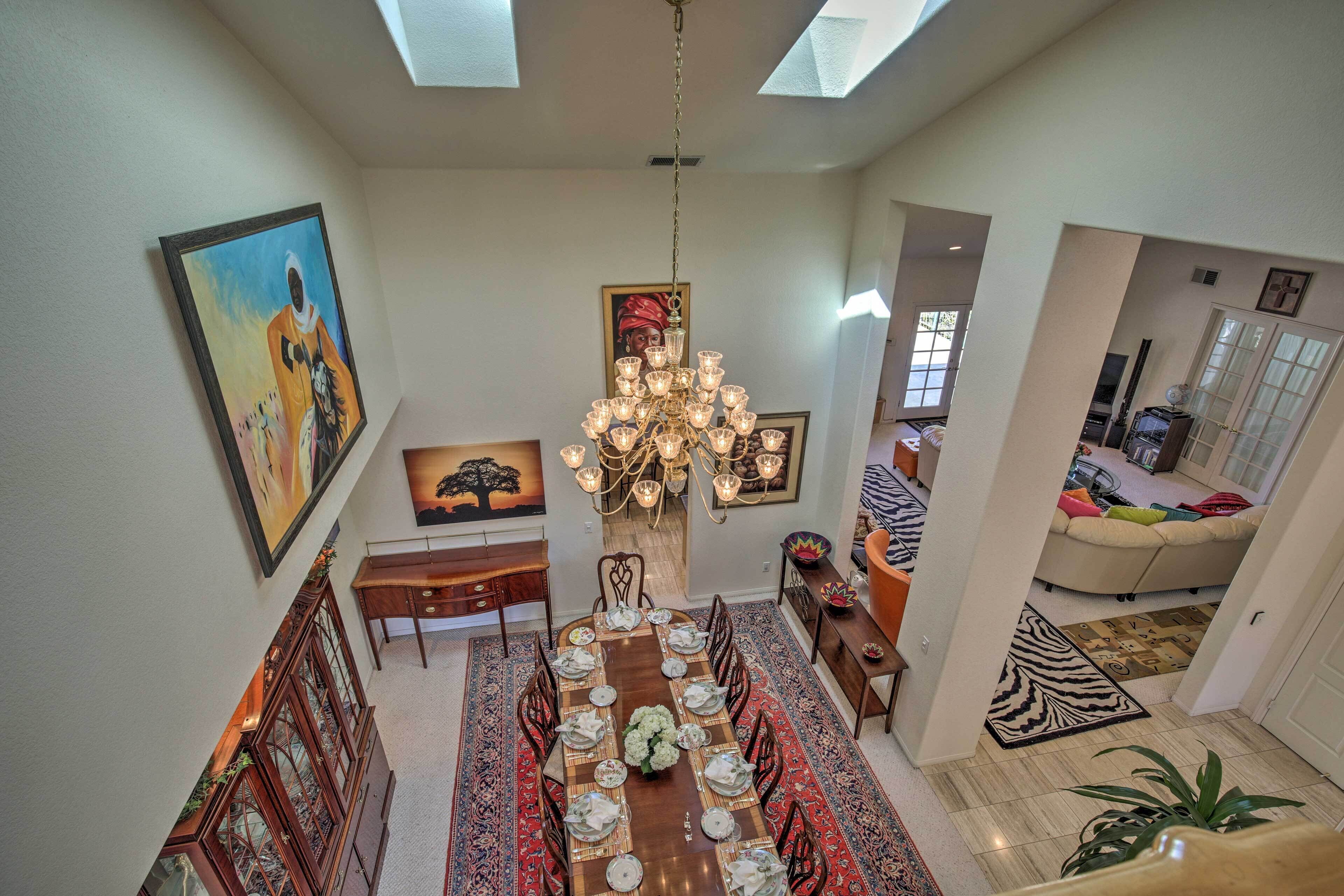 A dining area with a long table set for a meal, a chandelier, and artwork on the walls.