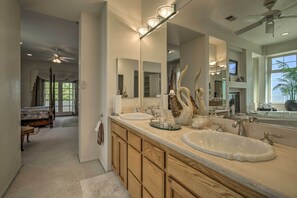 Spacious bathroom with a large vanity area, two sinks, and a mirror, flanked by cabinets and decorative accents.