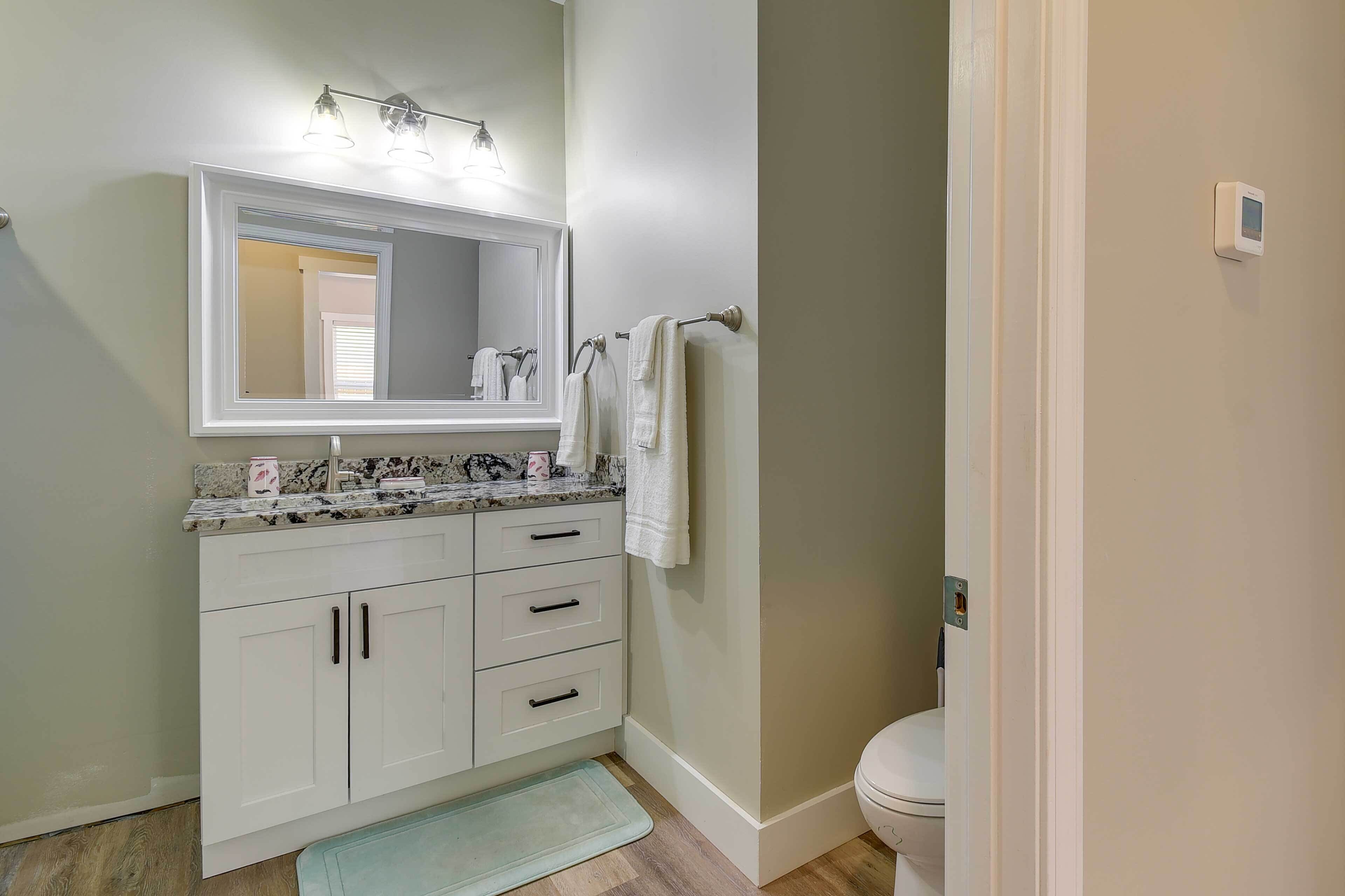 Een badkamer met een wit wastafelmeubel, een grote spiegel en een toilet.