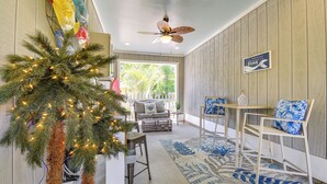 Un espace intérieur chaleureux et accueillant, avec un ventilateur de plafond, un sapin de Noël illuminé, un canapé, une table basse et un tapis.