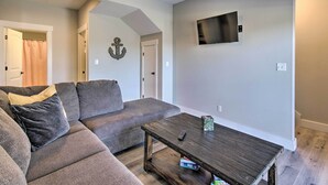 A living room with a grey sofa, a wooden coffee table, and a flat-screen TV mounted on the wall. - Lampe Retreat w/ Pool Access - Walk to Lake! (Lampe)